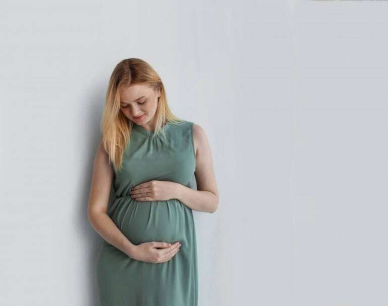 Young woman holds pregnant belly